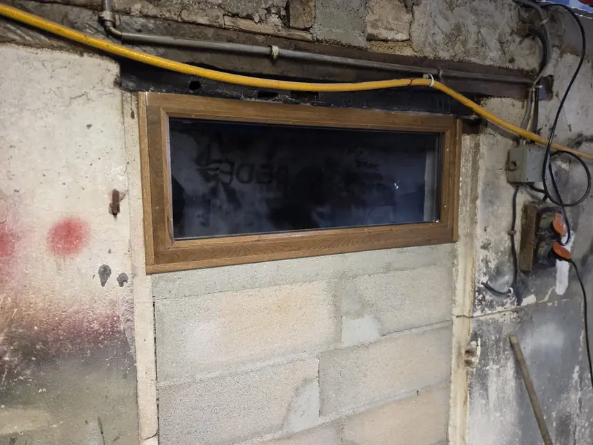 Petite fenêtre bois sur mesure posée dans un mur de cave en pierre